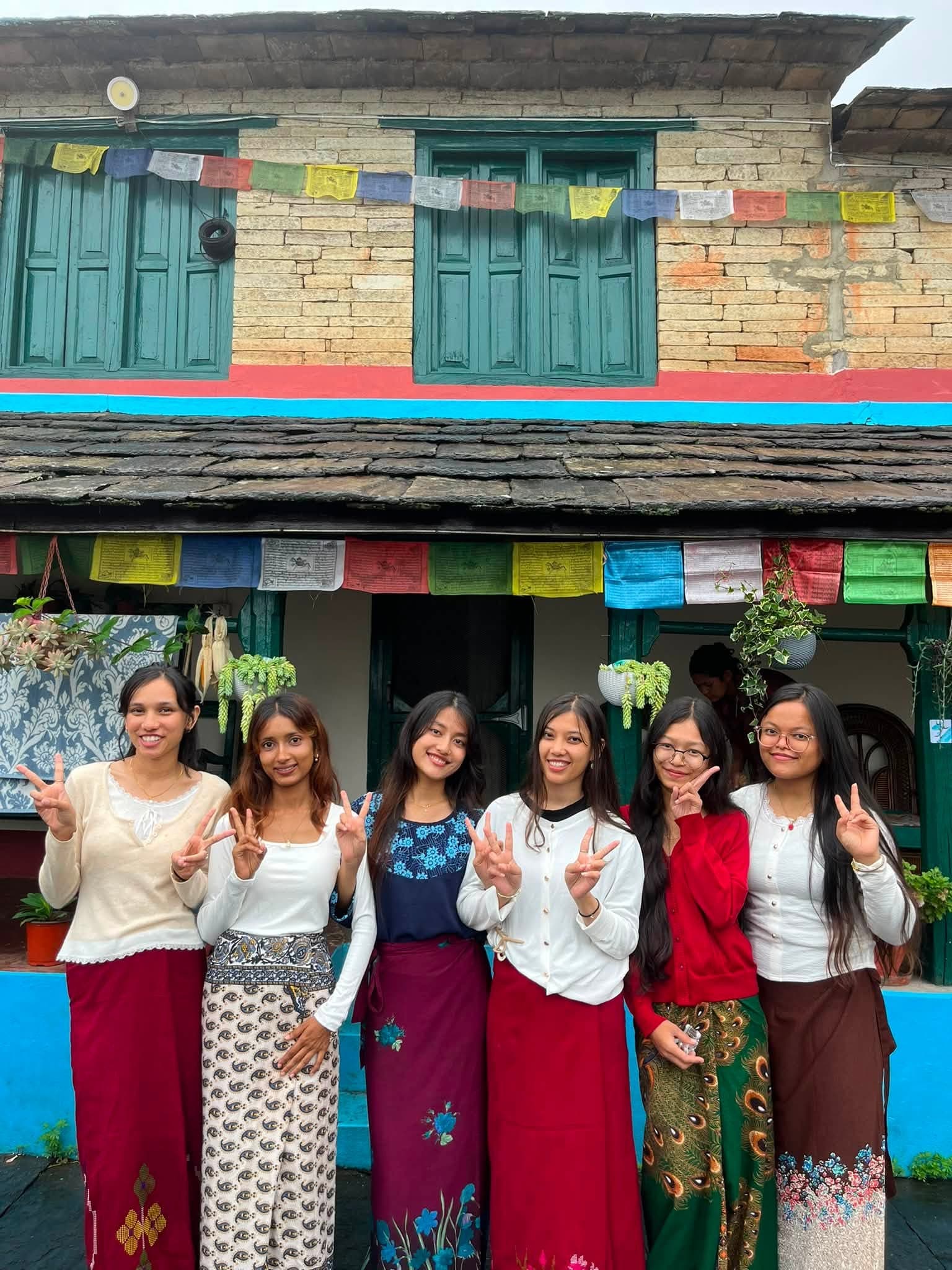 Students outside a traditional house at Sirubari