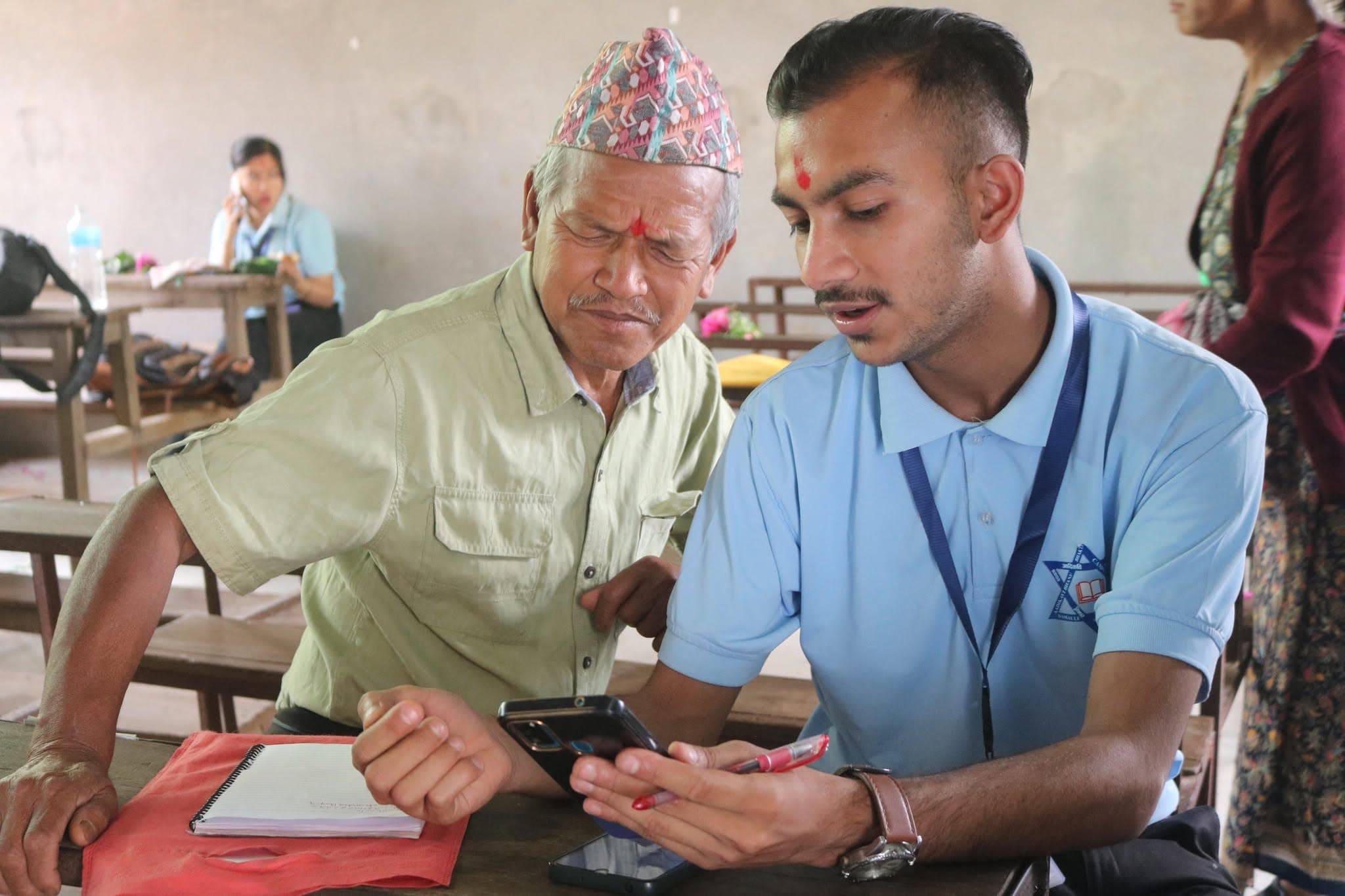 A student helping an elderly participant with his phone