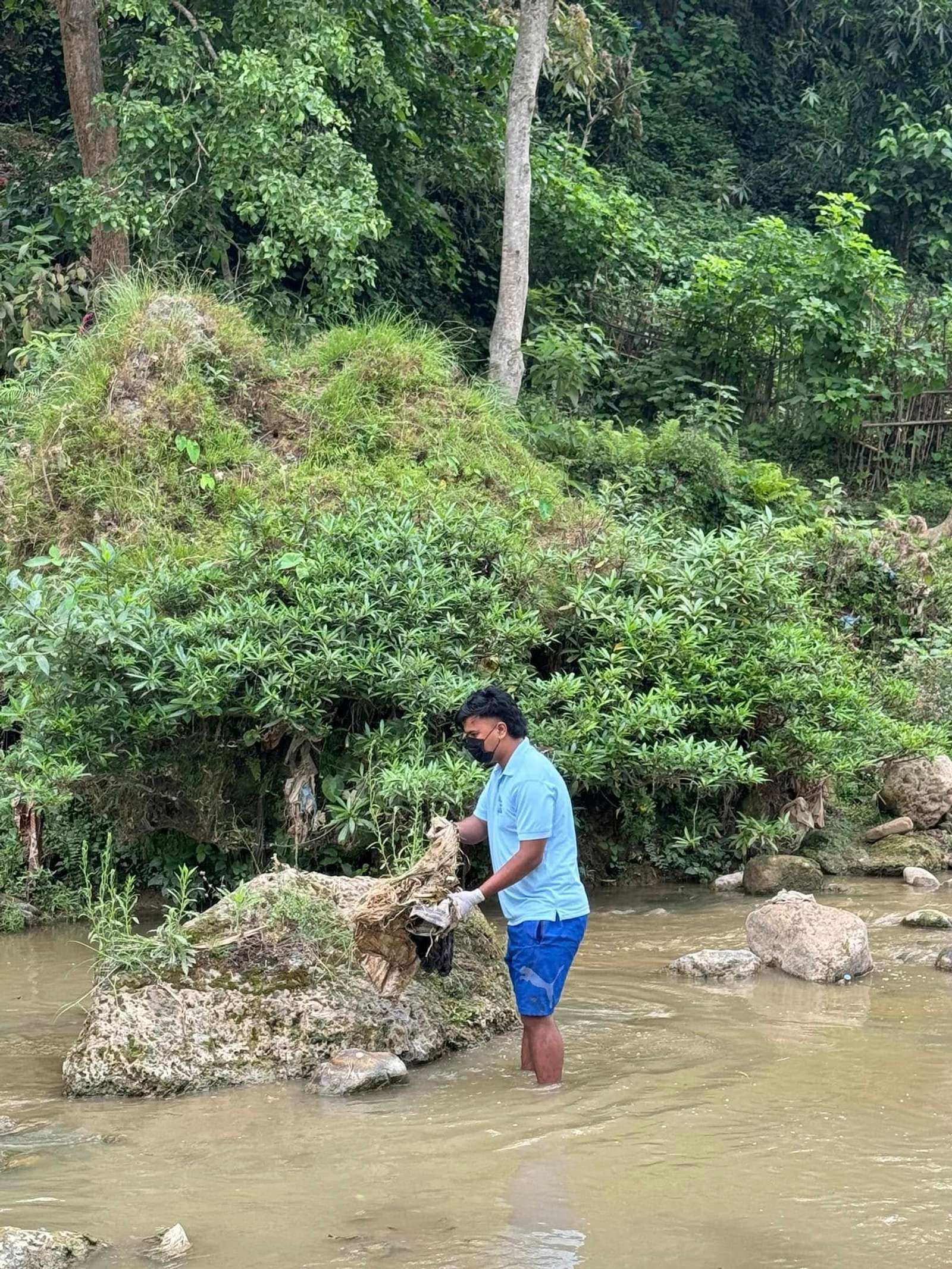 Pulling waste out from between the rocks along the bank